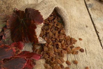 Golden raisins in burlap bag over wooden table