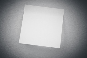 A blank sticky note with a notebook on the wall 