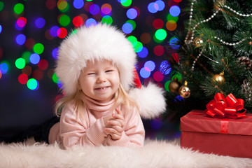 Fototapeta na wymiar funny baby in Santa Claus hat on bright festive background