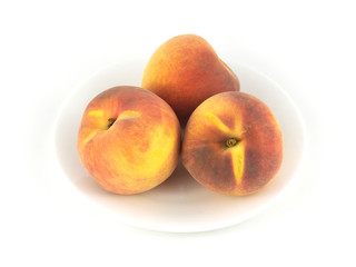 Three fresh Peaches on plate isolated on white close up