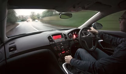 Photo sur Plexiglas Voitures rapides Un homme conduit une voiture à grande vitesse par temps humide.