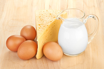 Big piece of cheese, glass jug with milk