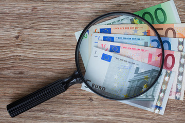 euro banknotes under magnifying glass