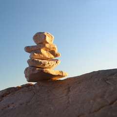 Fototapeta na wymiar Stone pyramid on the rock at sunset