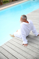 Senior man with spa bathrobe relaxing by pool