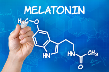 Hand mit Stift zeichnet chemische Strukturformel von Melatonin