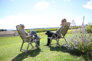 Senior people relaxing in long chairs in countryside