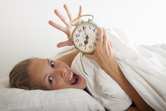 Young sleeping woman and alarm clock in bed