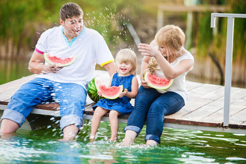 Fototapeta na wymiar happy family on picnic in the green park with lake