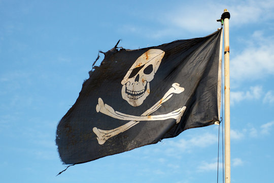 Piratenflagge gegen blauen Himmel. Piraten Flagge im Wind, die den Schädel  und die Kreuzbeine als Symbol der Piraten. Platz für Text Stockfotografie -  Alamy