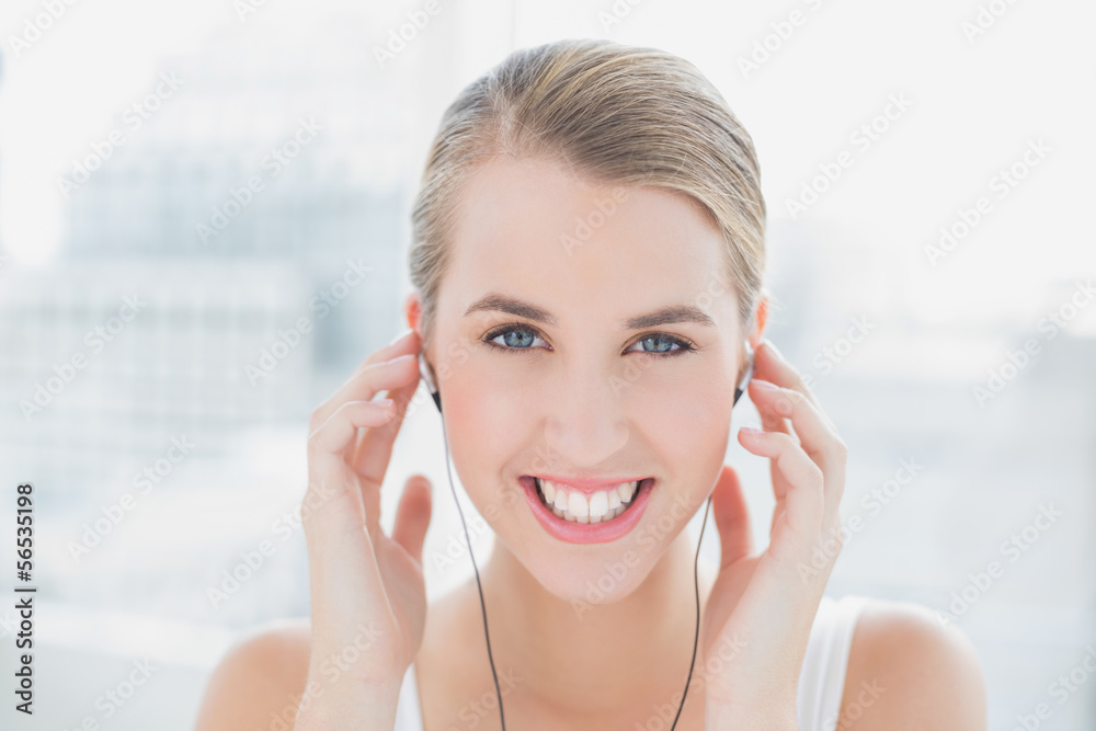 Wall mural Close up on smiling sporty woman listening to music