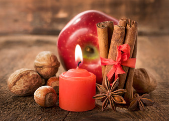 Fototapeta na wymiar apple with nuts, star anise , cinnamon and a candle