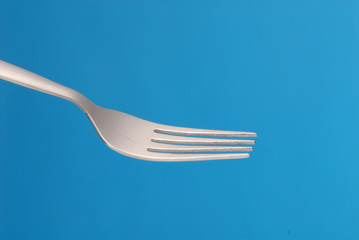 Detalle de un tenedor sobre fondo azul.
