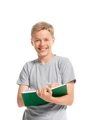 Happy teenage boy writes something in a notebook