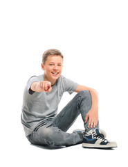 Teenage boy sitting on the floor and points at the camera