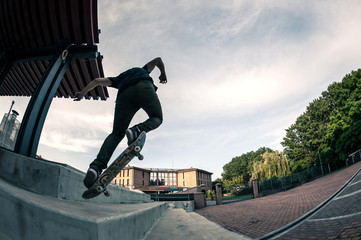 Skateboarder jump in the street from below.