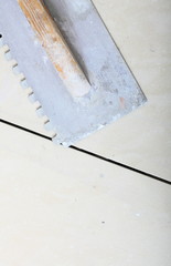 building work tool dirty trowel on new tile floor surface