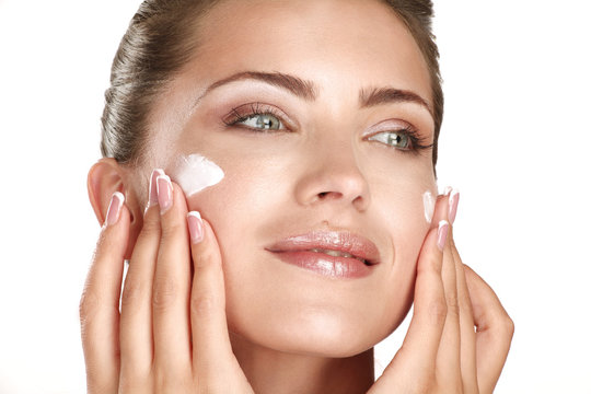 beautiful model applying cosmetic cream treatmen on her face