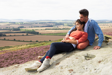 Fototapeta na wymiar Young Couple Sitting On Rock Admiring View