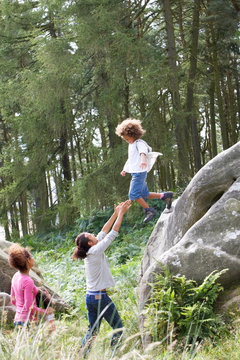 Father Helping Son To Jump Off Rocks