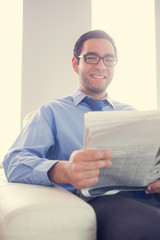 Content man looking at camera and holding a newspaper sitting on