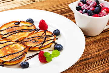 pancakes with chocolate and berries on white plate