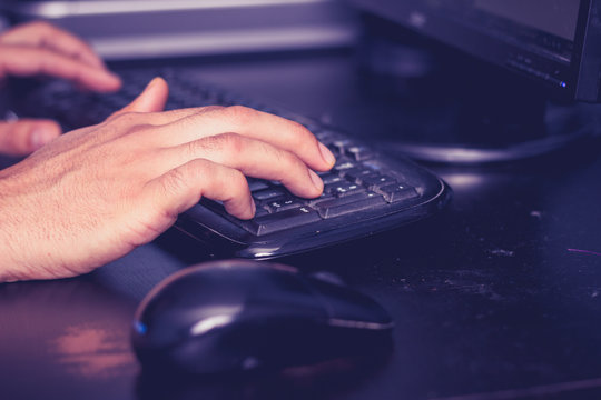 Male hands typing on keyboard at desk