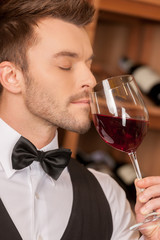 Confident sommelier. Side view of confident young sommelier hold