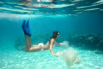 Underwater shoot of a girl in bikini playing with the sand in th