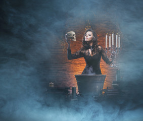 A young and sexy witch making a deadly poison with a skull