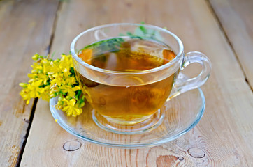 Herbal tea from tutsan in a glass cup on a board