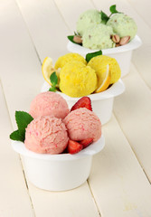 Tasty ice cream scoops in bowls, on wooden table