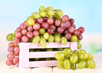 Ripe green and purple grapes in wooden box
