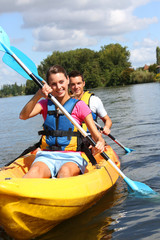 Couple riding canoe in river