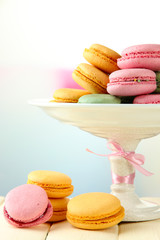 Gentle macaroons in vase on table on light background
