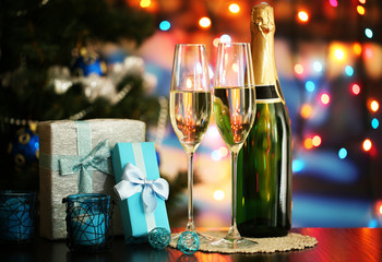 Glasses of champagne and gifts on bright background