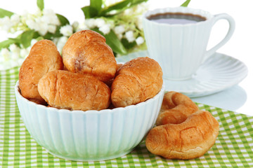 Tasty croissants and cup of coffee on table on white background