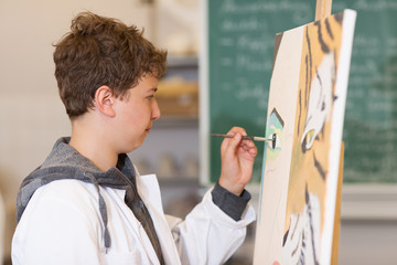 Schüler malt an der Staffelei