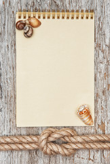 Ship rope, shells, notebook and wood background