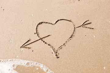 heart with an arrow written on the sand