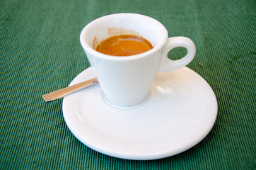 White espresso cup standing on the green textile tablecloth