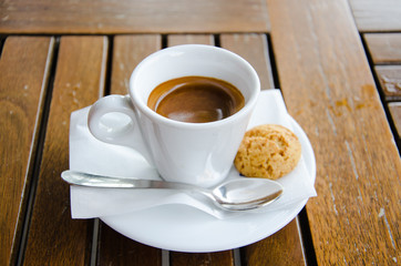 White espresso cup with biscuit standing on the wooden table