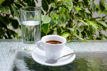 White espresso cup with glass of cold water