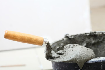 Dirty trowel and bucket on building site. Renovation at home