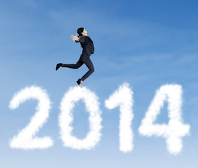 Fototapeta na wymiar Businesswoman jumping over clouds of 2014