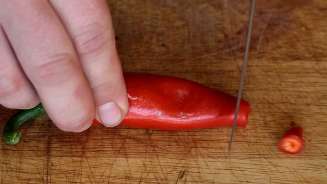 Cutting red papper  on wooden plate closeup