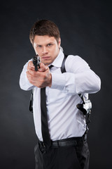Naklejka premium Bodyguard. Confident young man in shirt and tie holding gun and