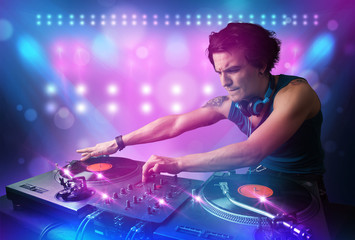 Plakat Disc jockey mixing music on turntables on stage with lights and