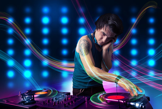 Young Dj mixing records with colorful lights