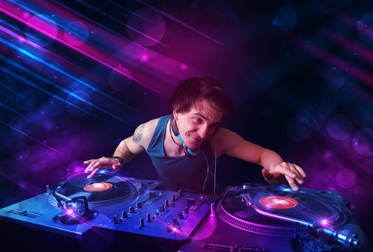 Young DJ playing on turntables with color light effects